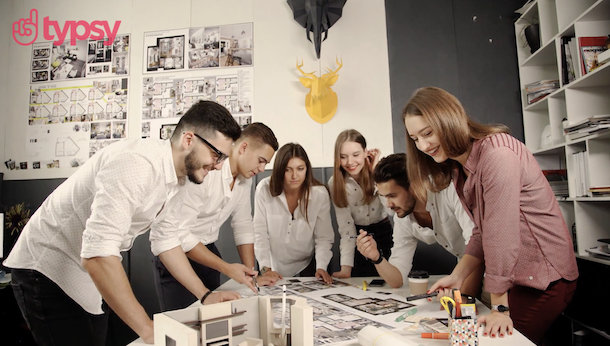 A group of people gather together around an office table.